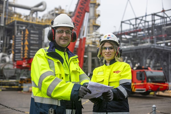 two colleagues smile at the camera while reviewing plans